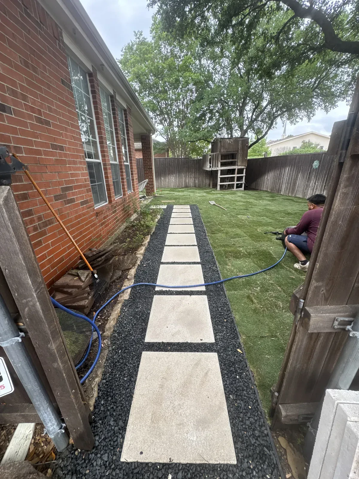 Concrete stepping stones set in dark gravel beside a brick home